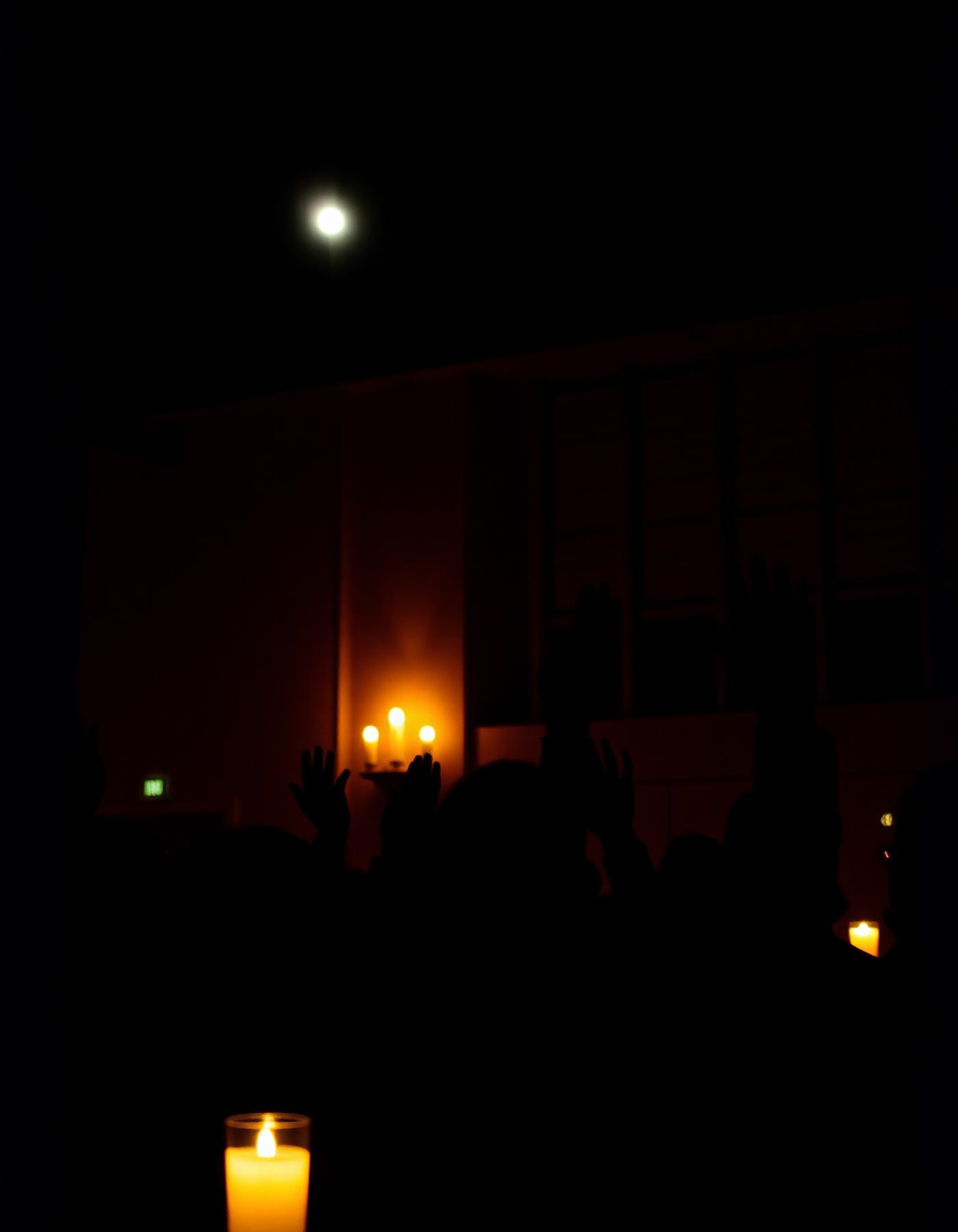 Hands raised voting in a candlelit hall